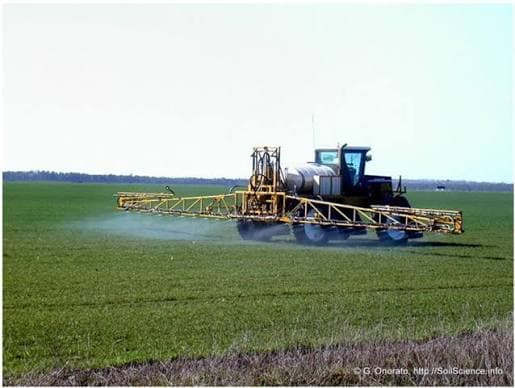 A modern tractor equipped with sensor booms spraying a field with a digital overlay map